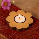 Flower-shaped candle holder with a lit candle on a patterned fabric background
