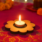 Floral-shaped candle holder with a lit candle on a red fabric background