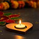 Heart-shaped mdf tealight candle holder with a lit candle on a dark surface, surrounded by colorful Diwali decorations.