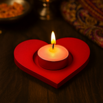 Red handpainted heart-shaped mdf candle holder with a lit candle on a dark surface