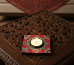 Decorative handpainted mdf tealight candle holder with a lit candle on a wooden surface