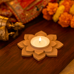 MDF lotus-shaped candle holder with a lit candle on a wooden surface.