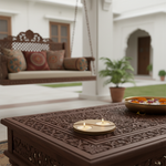 Decorative wooden table with mdf tealight candle holder and a bowl on a patio with a swing and plants in the background.