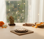 Decorative setup with a lit candle, figurine, and flowers on a table with a blurred background with DIY mdf tealight candle holder