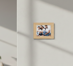 Wooden photo frame with a family portrait on a light gray wall