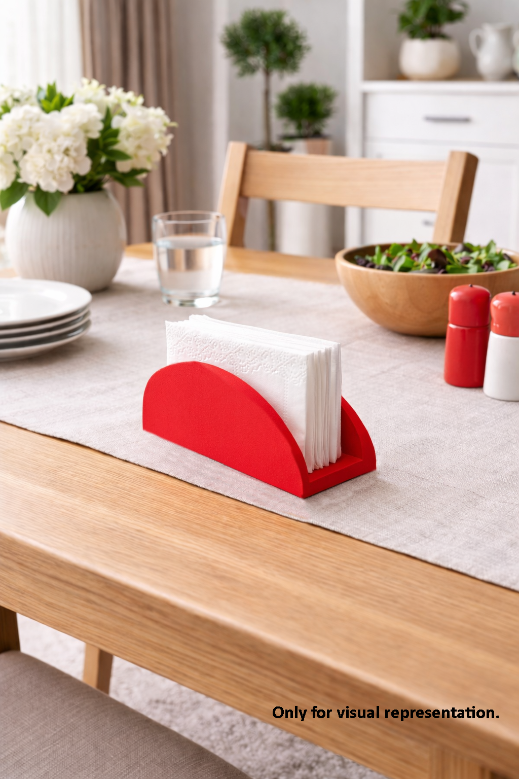 Red MDF DIY napkin holder with white napkins on a dining table with a glass of water and salad.