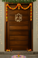 MDF Ganesha wall decor on main door with marigold toran, rangoli and diya lighting.