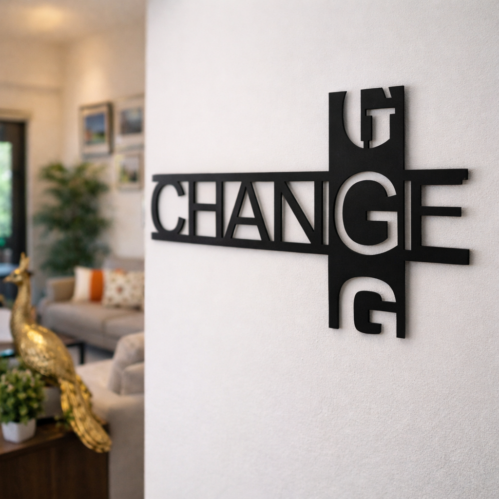 Modern black typography wall décor featuring the word “CHANGE” in a stylish geometric design mounted on a white wall in a contemporary living room setting.