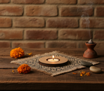 Candle, marigold flowers, and incense on a wooden surface with a brick wall background with mdf tea light candle holder.