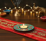 Decorative Diwali setup with a lit candle in a colorful Diwali lamp on a red cloth, incense sticks, and an elephant statue with handpainted mdf tea light candle holder.