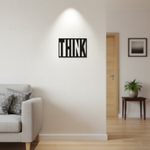 Black MDF wall décor with cut-out word “THINK” mounted on a light-colored wall in a modern living room setting.