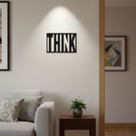 Black MDF wall décor with cut-out word “THINK” mounted on a light-colored wall in a modern living room setting.