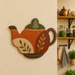 Colorful teapot-shaped MDF wall art with floral folk design mounted on a warm beige kitchen wall.
