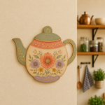 Colorful teapot-shaped MDF wall art with floral folk design mounted on a warm beige kitchen wall.