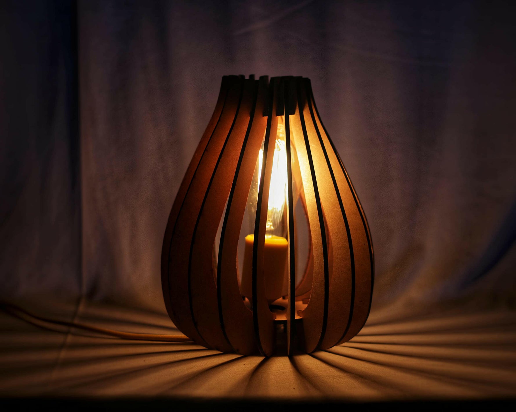 Elegant wooden MDF table lamp with a warm bulb, casting ambient lighting in a dimly lit space.