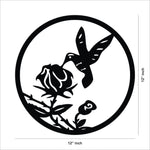 Circular hummingbird wall art in black featuring a bird hovering near a rose, the image shows the dimensions of the product that is 12 inch by 12 inch.