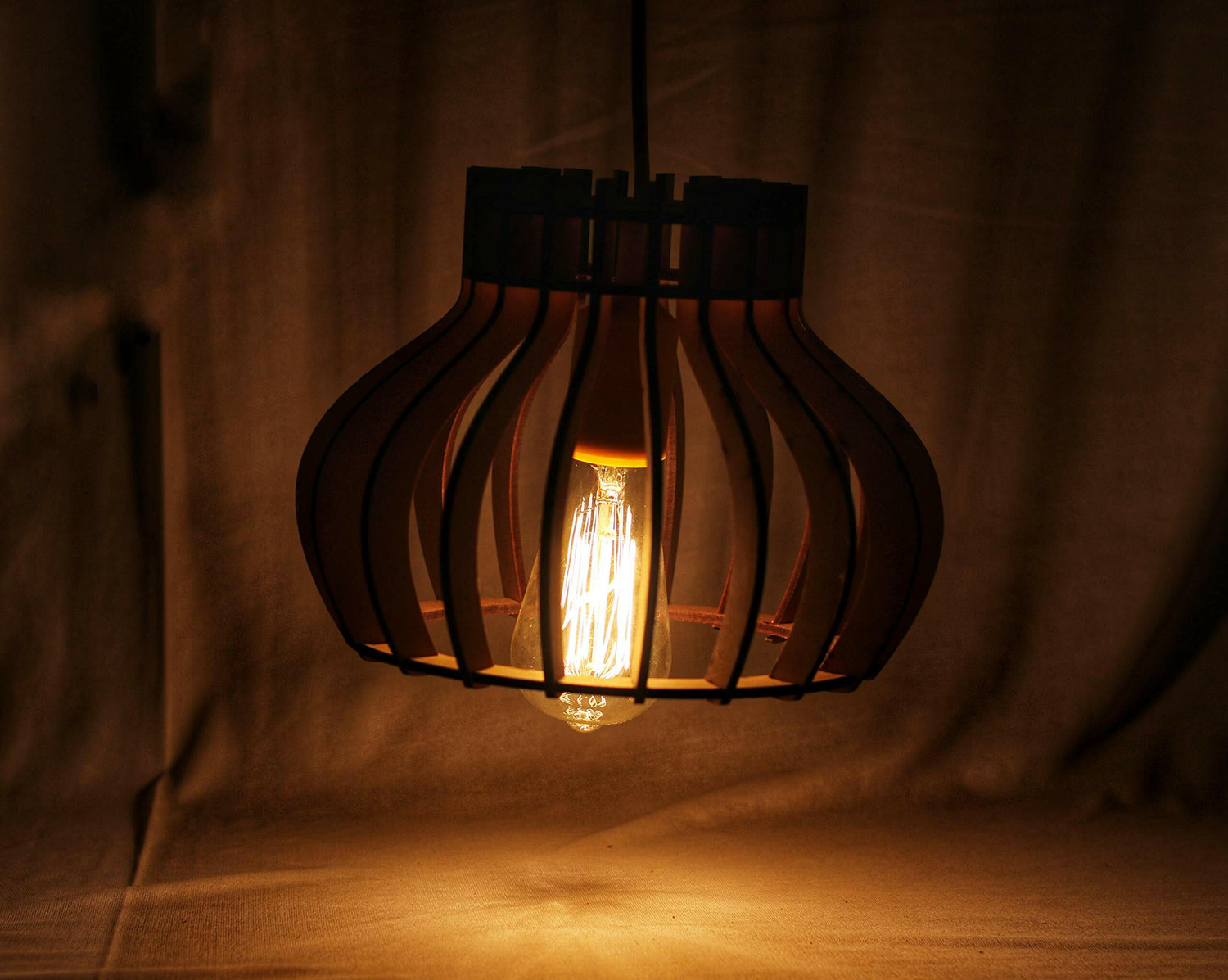 Matte black cage ceiling pendant lamp with glowing exposed Edison bulb and adjustable hanging cord