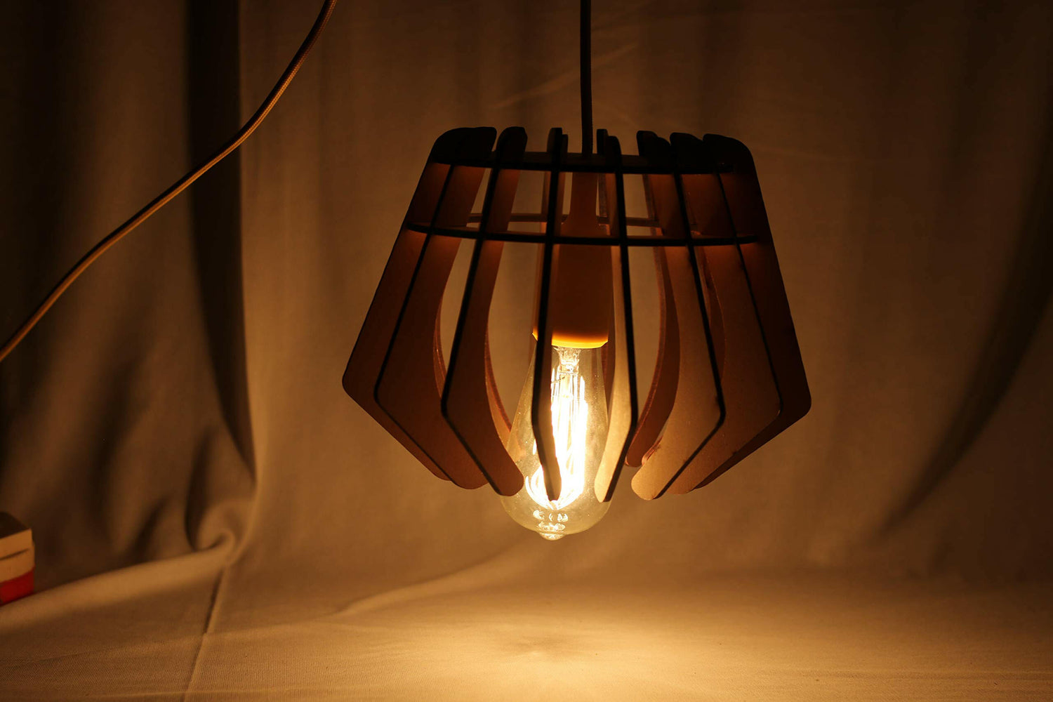 Matte black cage pendant ceiling lamp with glowing exposed bulb and black extension cord
