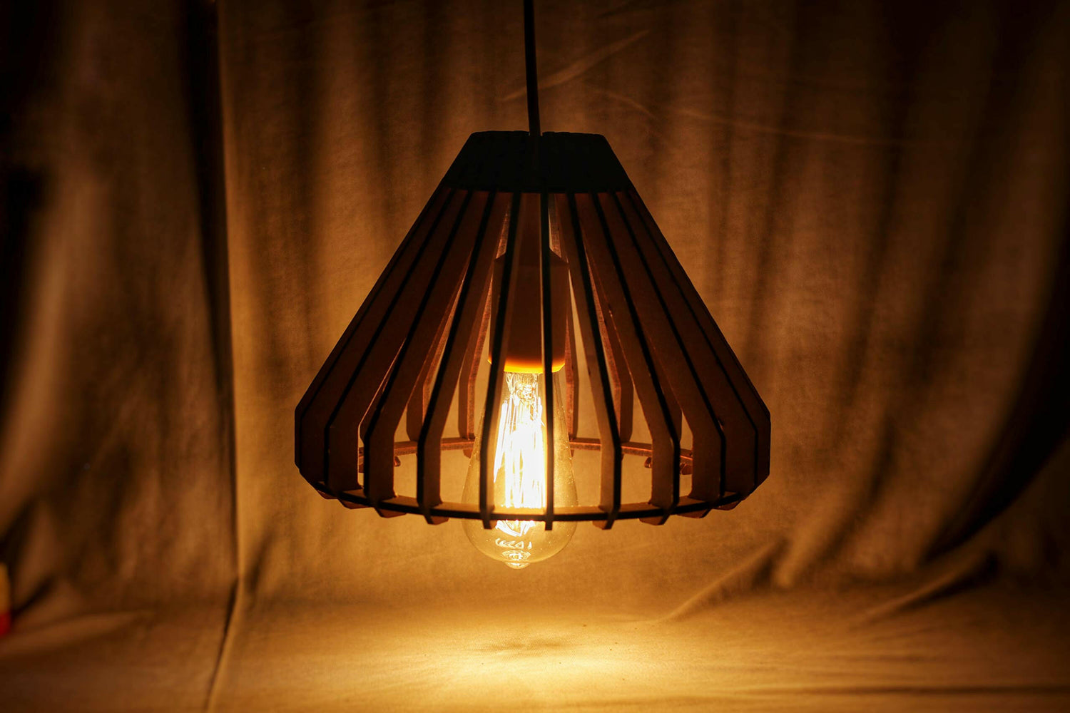 Matte black cage‑style ceiling pendant lamp with glowing Edison bulb and black hanging cord