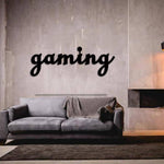 Gaming wall art in black script design mounted on a minimalist grey wall above a modern grey sofa in a cozy living space