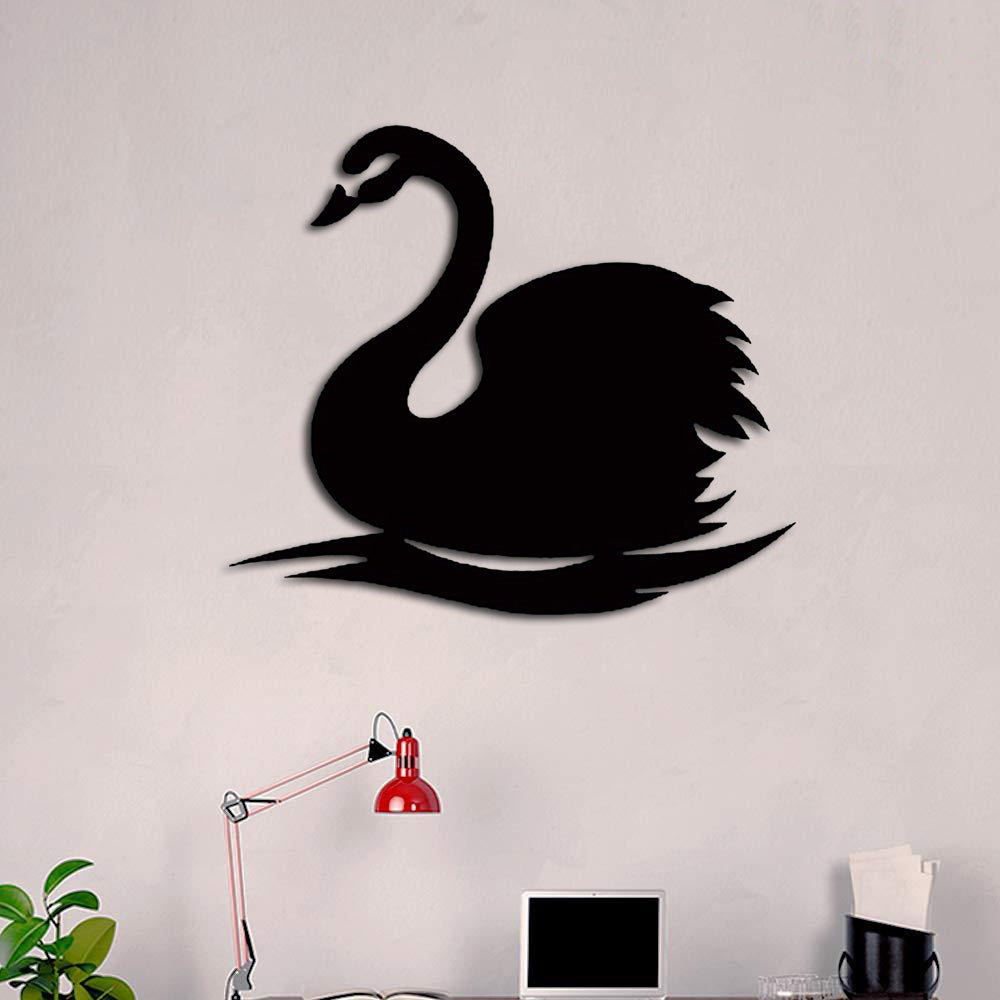 Black MDF swan wall decor mounted on a neutral-toned wall above a workspace with a red lamp.