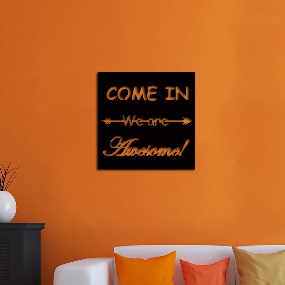 Wall art with the quote 'Come In, We Are Awesome!' featuring a playful arrow design, displayed on a vibrant orange wall above a modern white sofa with colorful cushions.