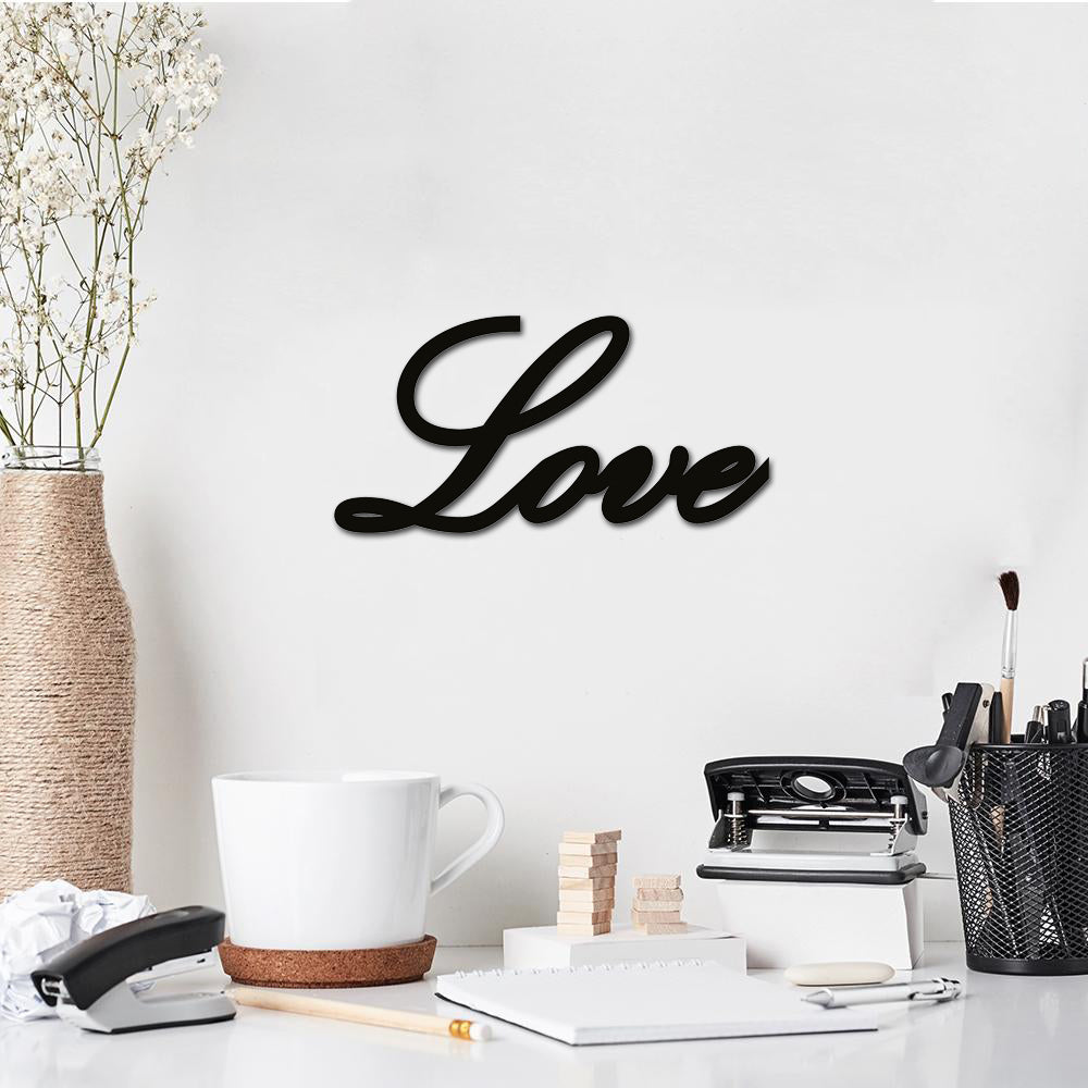  Black MDF wall art featuring the word "Love" in elegant cursive typography, mounted on a white wall above a workspace with a vase, cup, and office supplies.