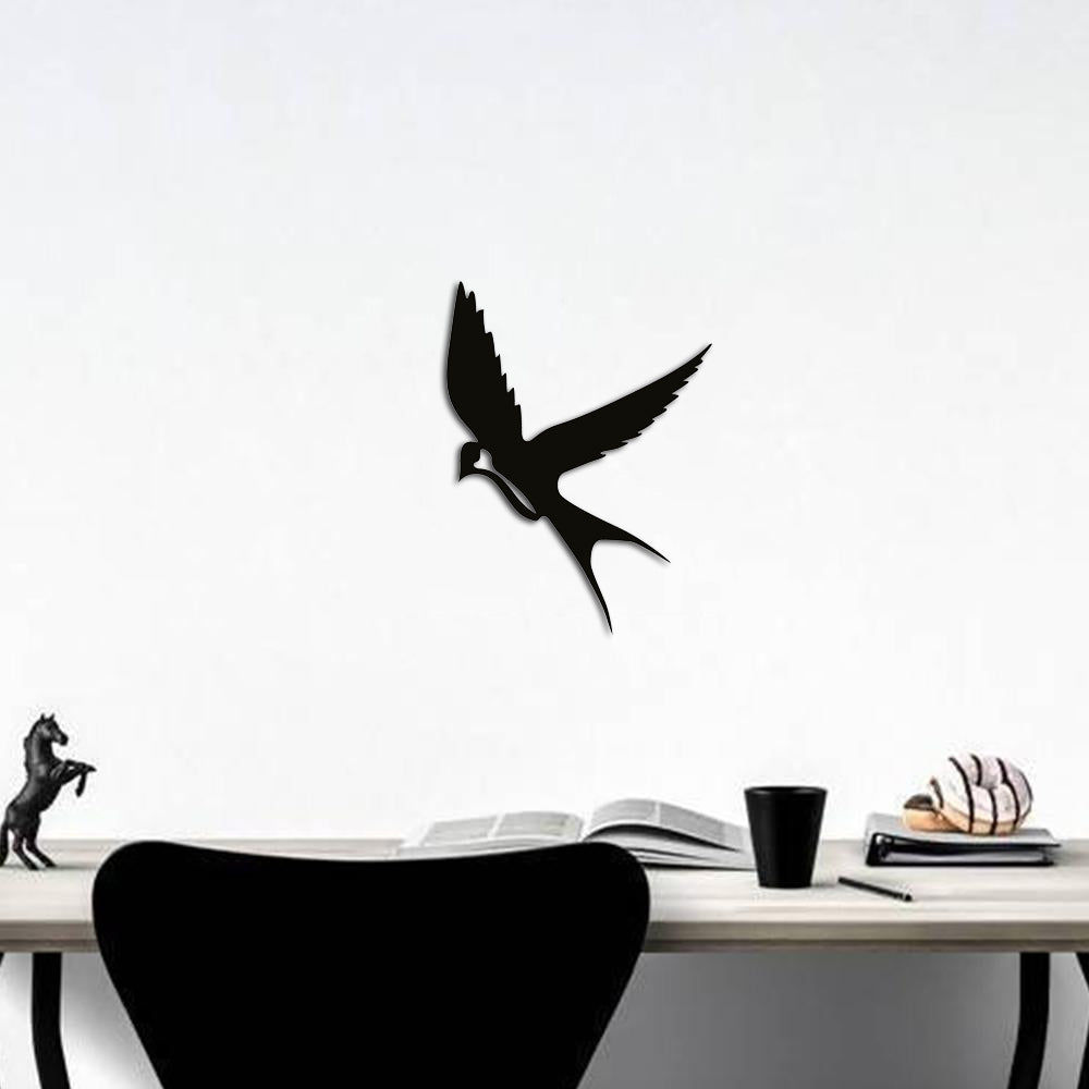 Black flying bird wall art featuring a sleek silhouette design, mounted on a white wall above a modern desk with minimalistic decor elements.