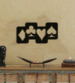 Black wall art featuring the four card suits—diamond, club, heart, and spade—mounted on a beige textured wall above a decorative console table.