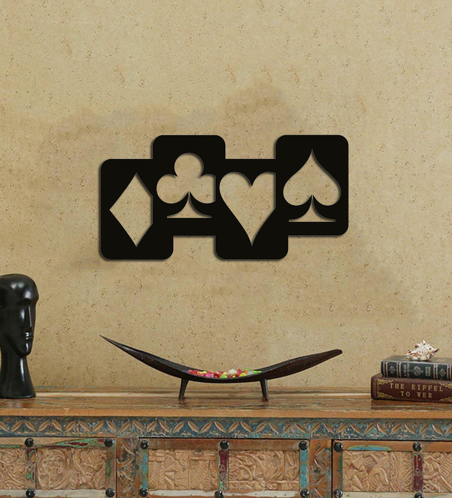 Black wall art featuring the four card suits—diamond, club, heart, and spade—mounted on a beige textured wall above a decorative console table.