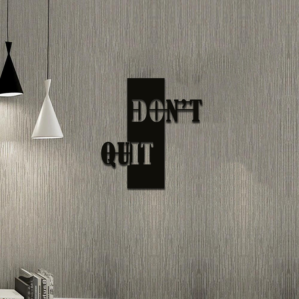 Motivational wall art with the phrase 'Don't Quit' displayed on a textured gray wall in a modern workspace.