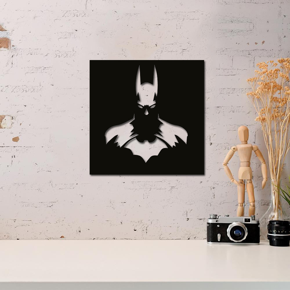 Batman wall decor featuring a sleek black and white silhouette design, mounted on a white brick wall above a minimalist desk with decorative items and a vintage camera.